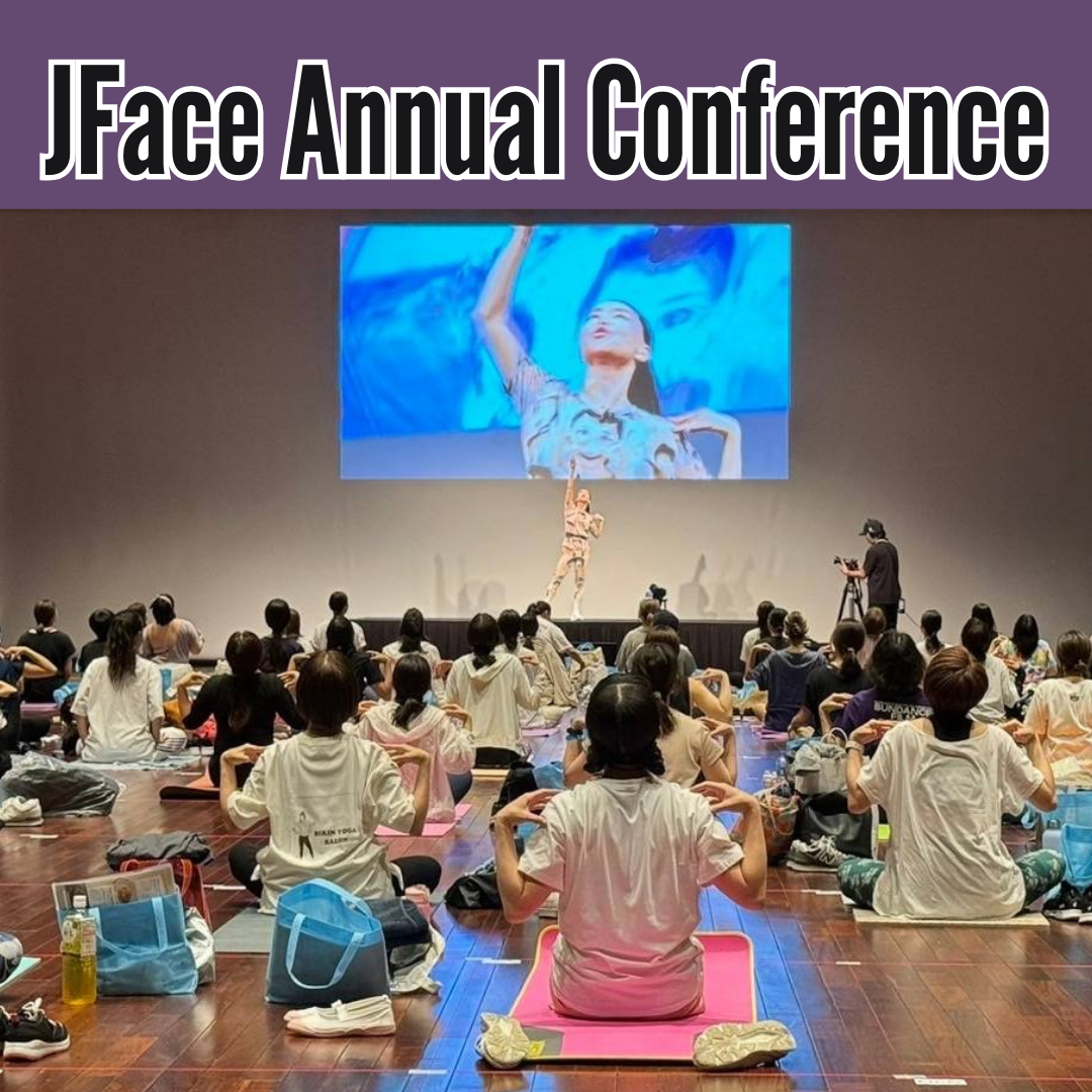 Image from the Koko Face Yoga Japan Tour, capturing a live event where participants engage in a guided face yoga session, led by an instructor on stage and displayed on a large screen, emphasizing active participation and learning in a group setting.