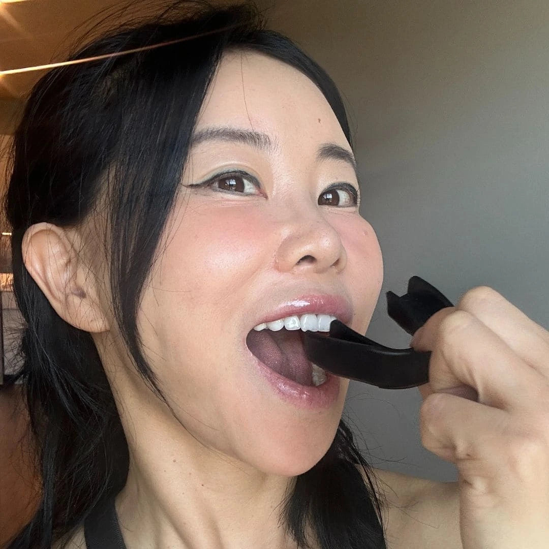 Face Yoga coach inserting facial aligner tool for muscle toning and anti-aging.